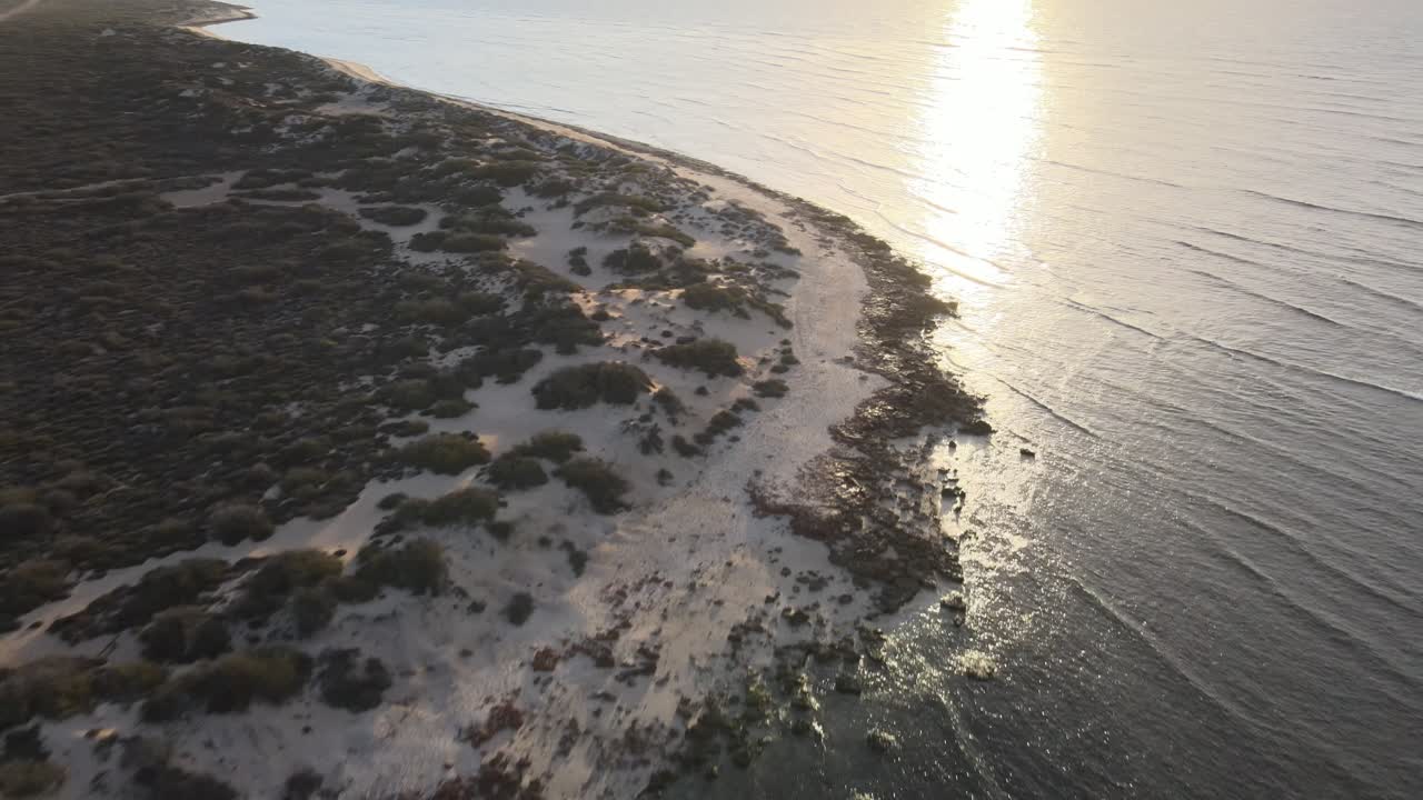 Dronekuvaus Exmouthin Ningaloo Reefin rannikosta auringonlaskun aikaan, liikkuen taaksepäin.