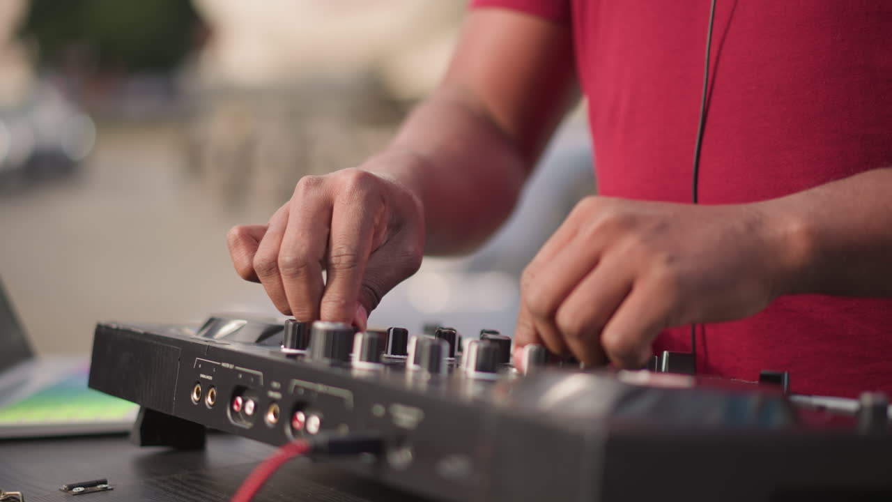 Disc jockey performing, Street performance with rhythmic mixing under warm afternoon sunlight, Disc jockey skillfully adjusting controls on portable mixer amidst energetic city environment