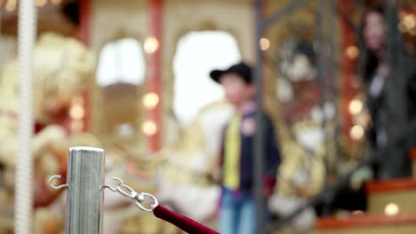 merry-go-round carousel. happy kids with parents riding carousel and taking pictures and selfies, children and adults take place, rope fence made from red velvet, employee opens door