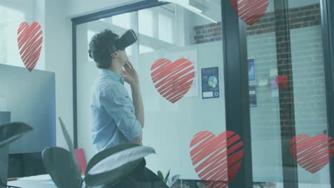 varios iconos de corazones rojos cayendo sobre caucásico que lleva auriculares vr en la oficina