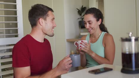 Happy-caucasian-couple-drinking-coffee-and-using-smartphone
