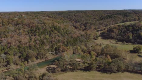 vuelo aéreo cerca de colinas junto a un río con la temporada de otoño acercándose