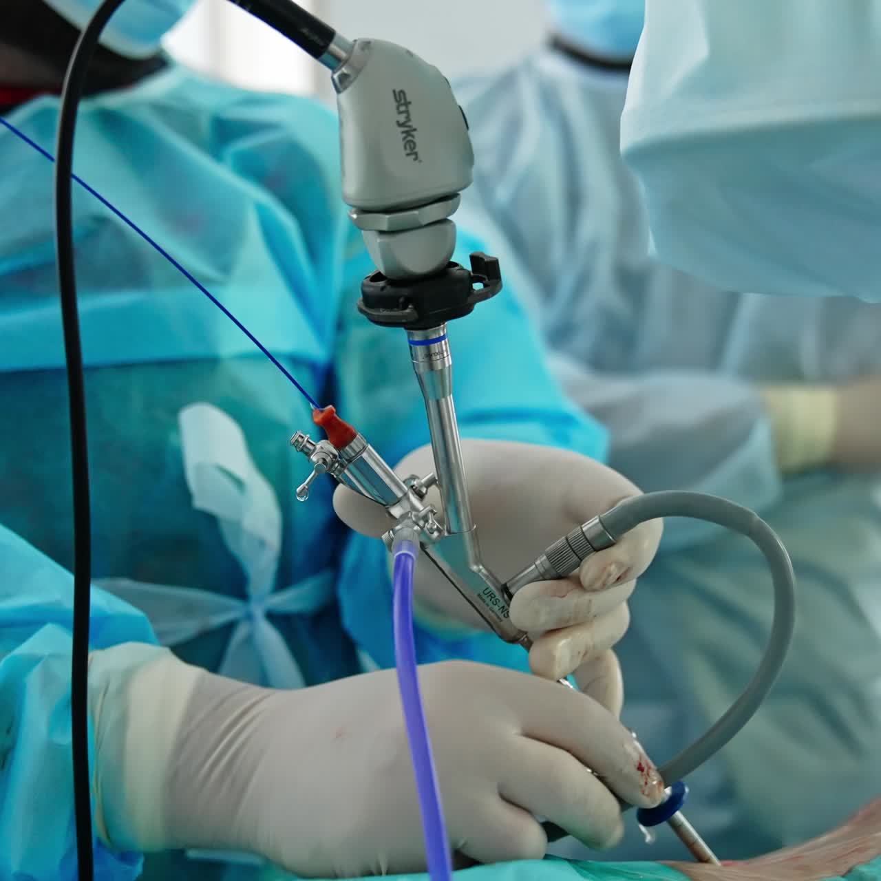 Usage of technological medical instrument during operation. Surgeon's hands hold the apparatus input into patient's body. Close up