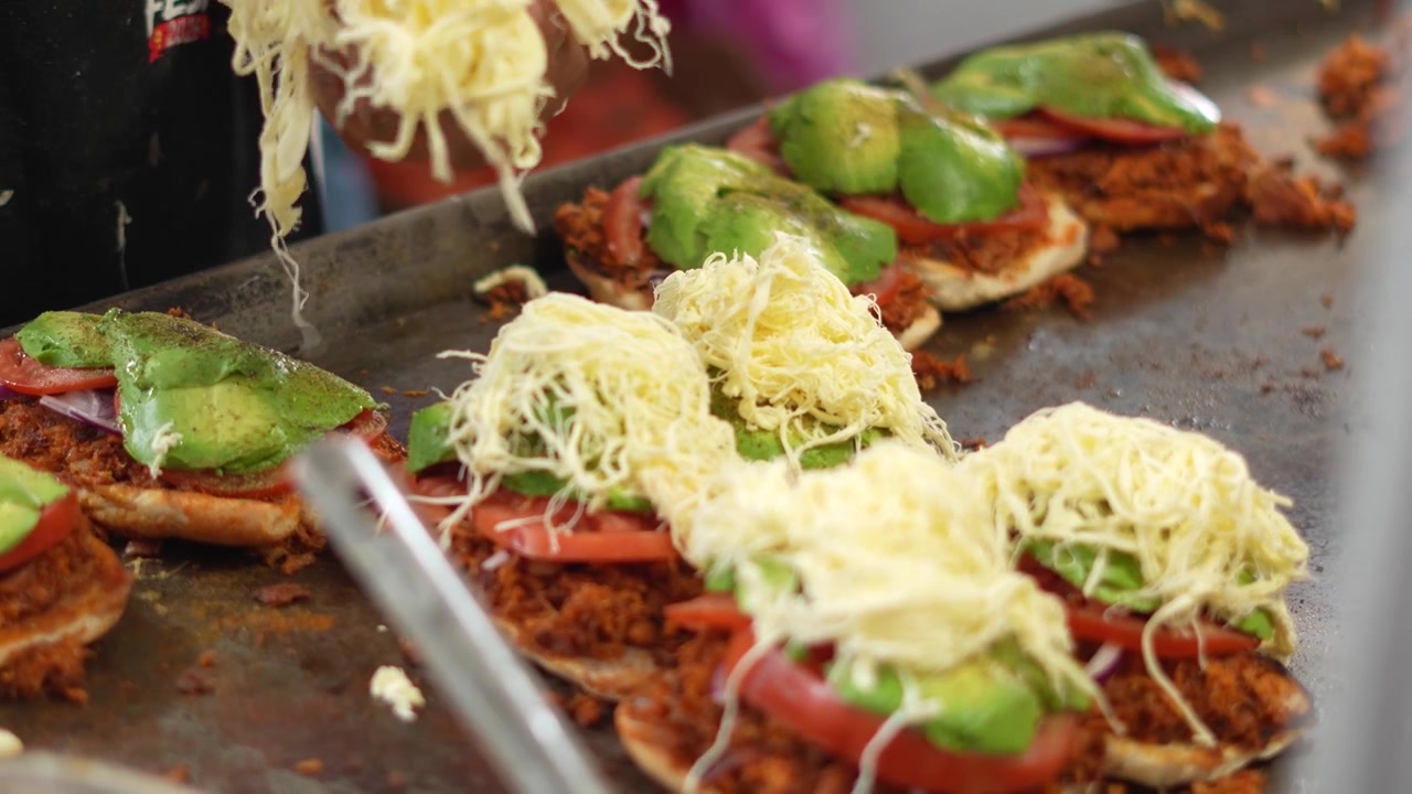 Nærbillede af kok, der tilføjer frisk ost på en berømt mexicansk torta, Mexico
