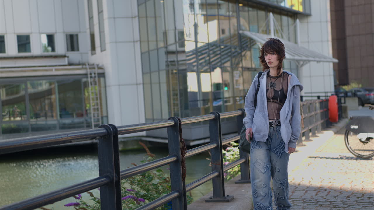 Outdoor Fashion Portrait Of Young Alternative Style Woman With Tattoos Walking Around Cananry Wharf In London Docklands Looking At Mobile Phone