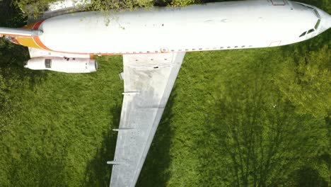vista aérea de arriba hacia abajo del avión abandonado en el campo verde en un día ventoso