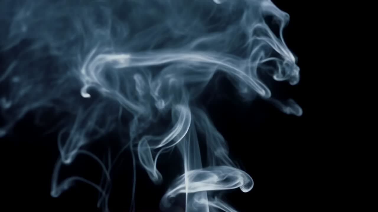 Nube di fumo blu-grigio che si alza formando viticci arricciati e diffondendosi in uno studio buio fuori campo