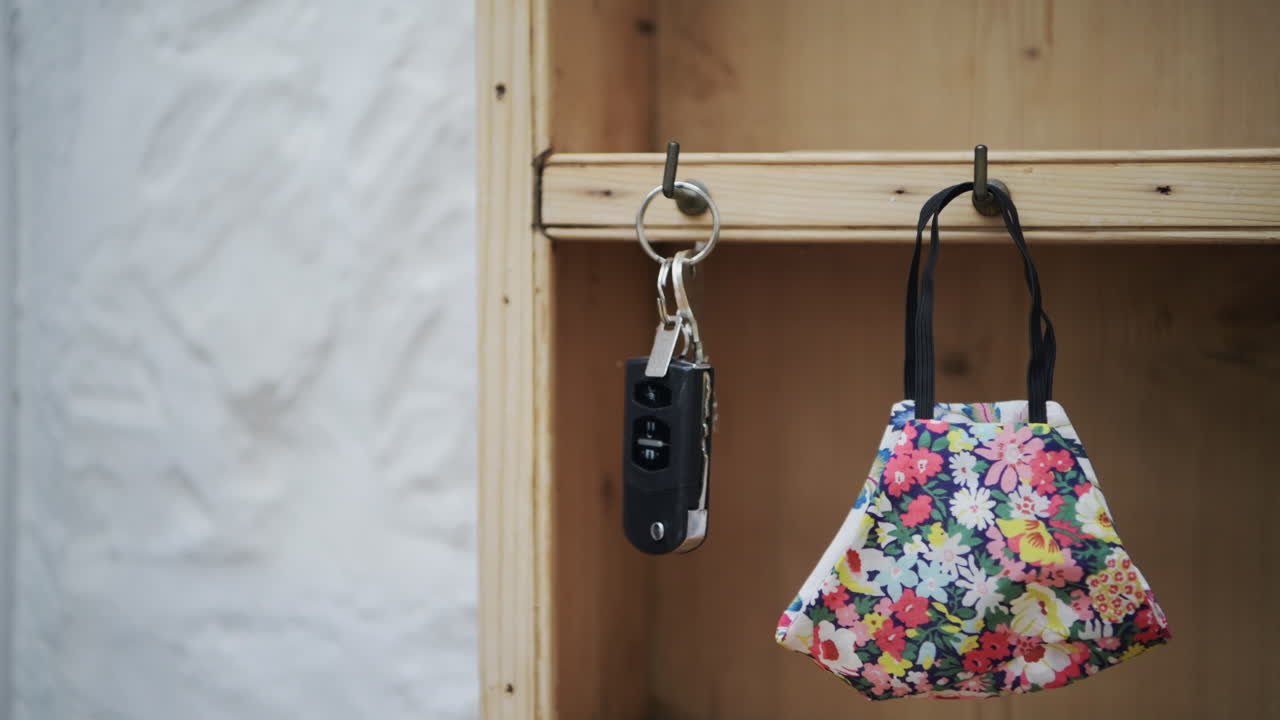 A tight shot of hanging up keys and face mask