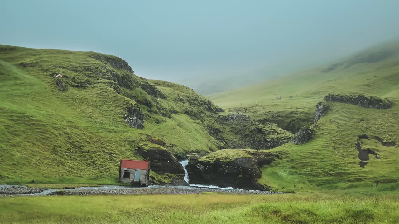 Time lapse of Icelandic landscape with a small hut and a small waterfall