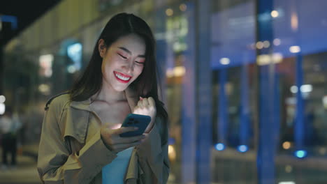 young woman using mobile phone in a city at night