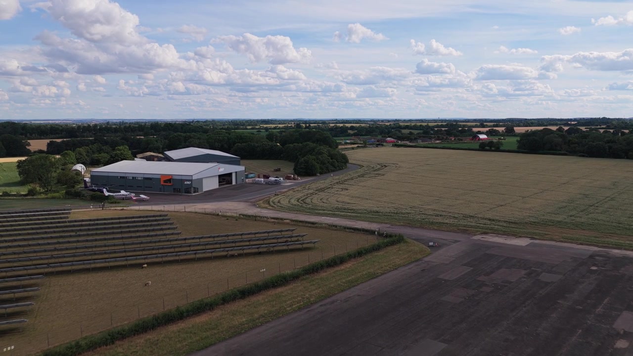 Lille landlig lufthavnsbygning omgivet af tørre landbrugsmarker under en blå himmel på en solrig sommerdag på landet i Frankrig.