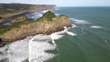 Luftaufnahme-Der-Wilden-Neuseeländischen-Küstenlandschaft-Mit-Schwarzem-Sandstrand-Und-Vulkanischen-Felsformationen