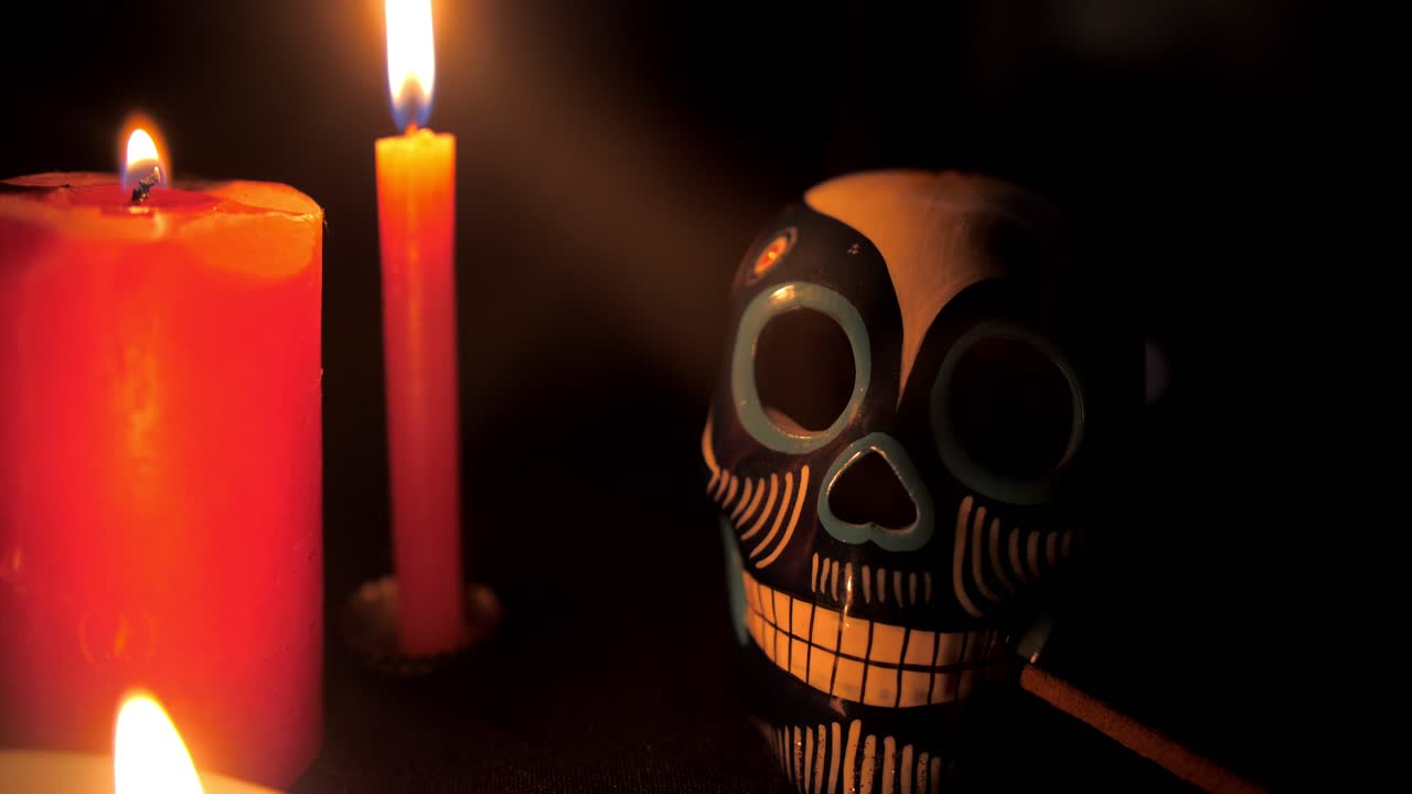 Zdobená lebka Calavera a zapálené svíčky ve tmě