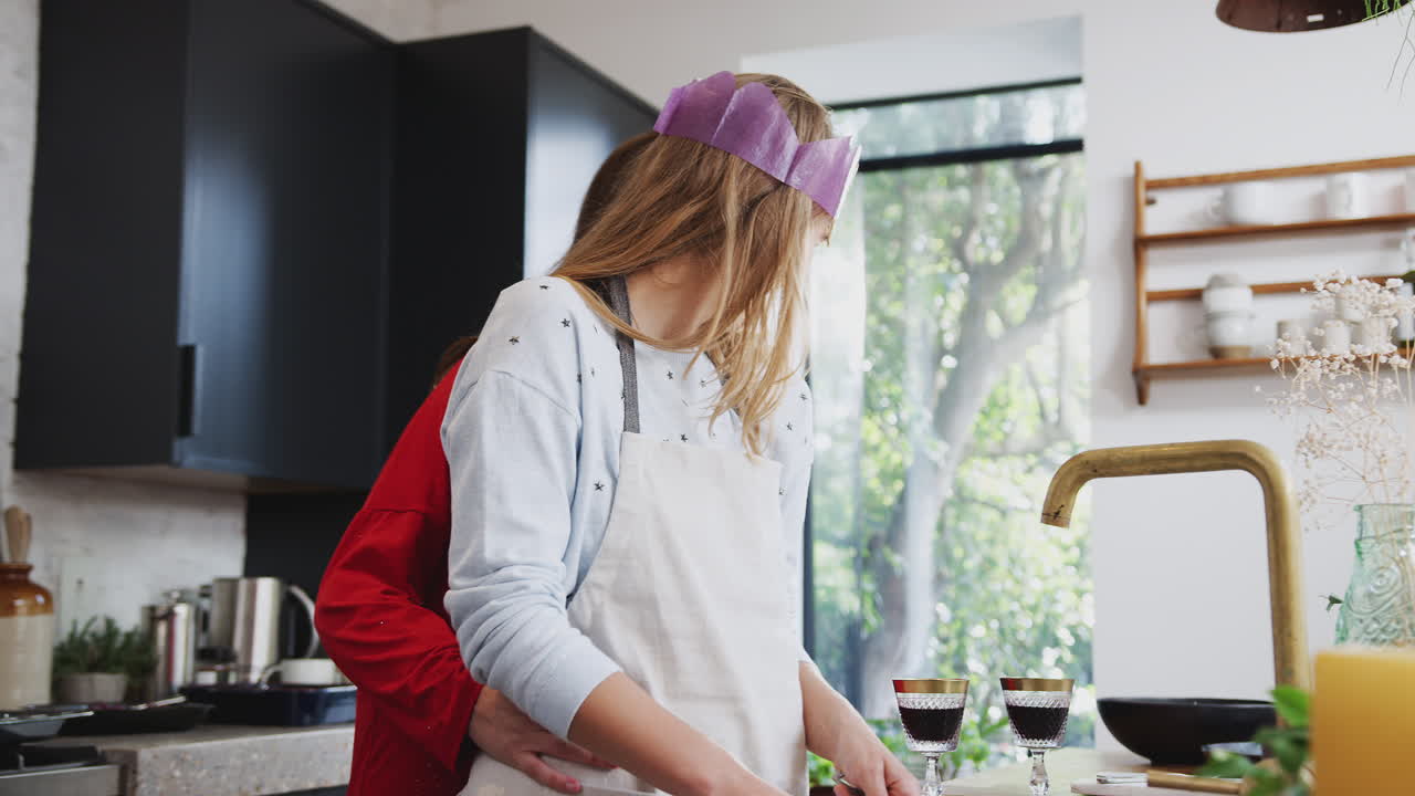 크리스마스 날 저녁 식사 후 주방에서 와인을  ⁇ 고 술을 마시는 동성애 여성 커플