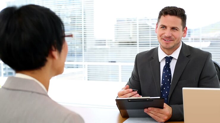 Handsome businessman talking with interviewee holding clipboard
