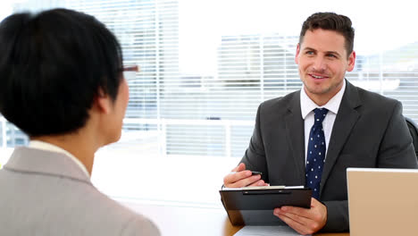 handsome businessman talking with interviewee holding clipboard