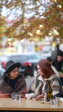 women friends enjoying coffee at an outdoor cafe in autumn