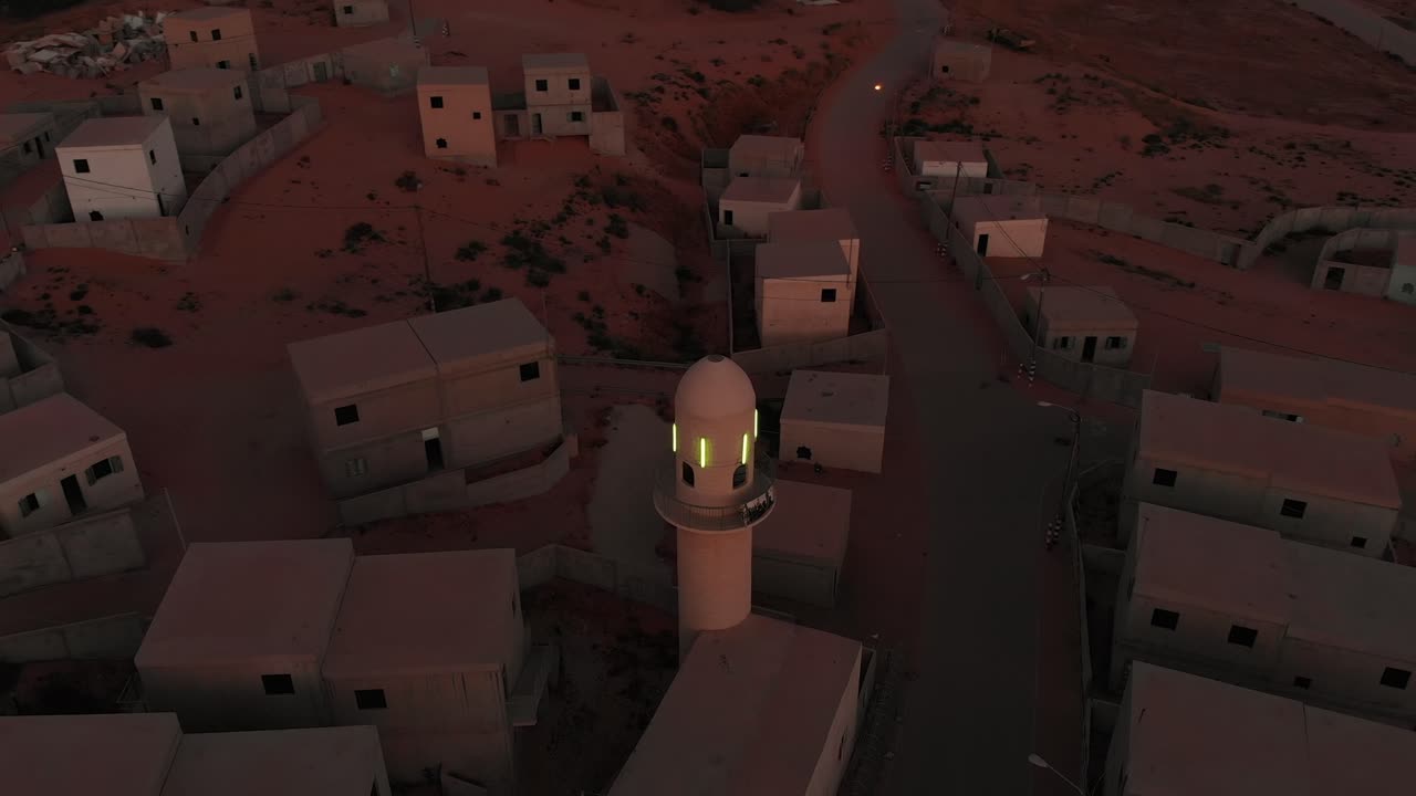 aerial view orbiting a mosque with green shining lights at morning of an empty arabic city near gaza in palestine