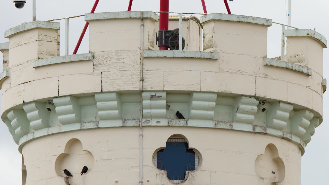Black pirate flag unfurls atop stone castle tower, overcast daylight, steady camera, close-up view