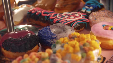 4k close-up slow motion footage of many different unhealthy donuts - with different colorful and sweet toppings - close shot - american junk food - voodoo doughnuts in portland