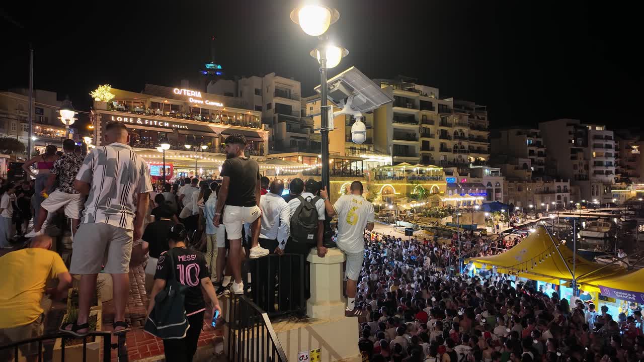 Nighttime gathering of a large crowd in an illuminated urban area