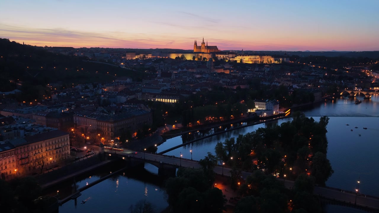 Veduta aerea ad alta quota del Castello di Praga e della Cattedrale di San Vito illuminati a giorno al crepuscolo sopra il fiume Moldava e il Ponte Carlo, Praga, Repubblica Ceca