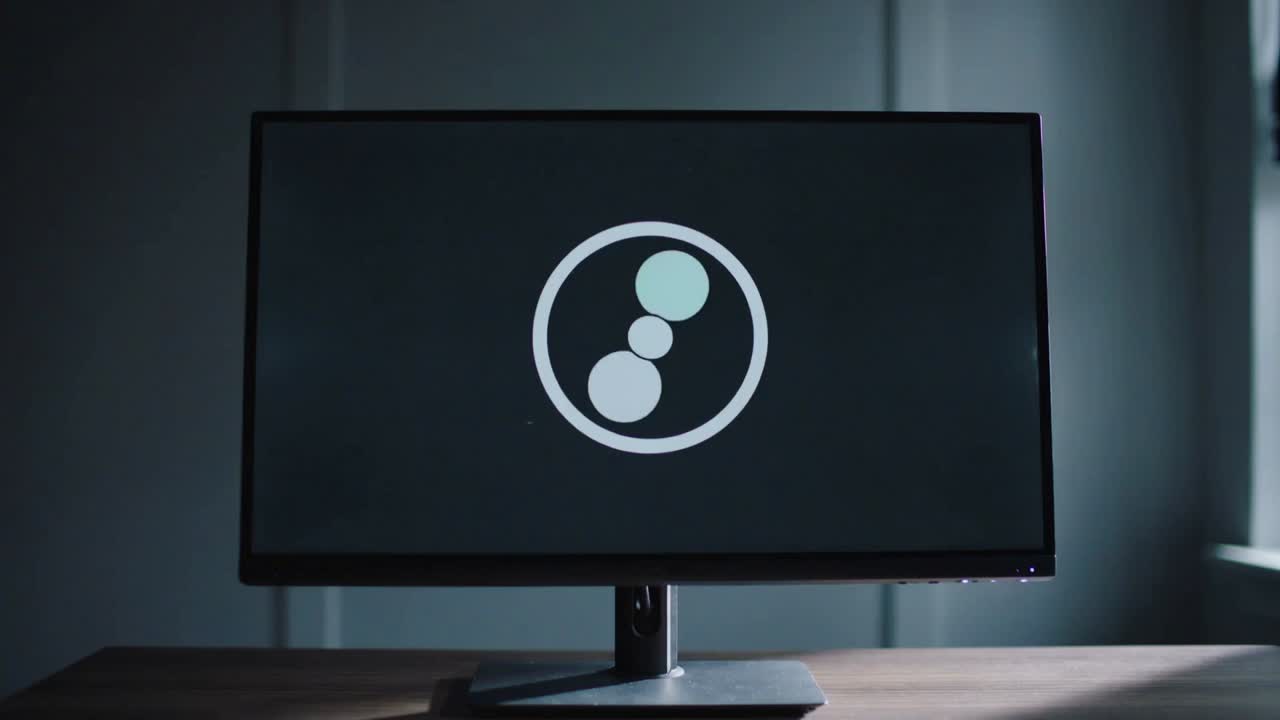 Spillende animasjon, widescreen-skjerm som viser roterende logo med tre sirkler på et skrivebord, merkevarebygging