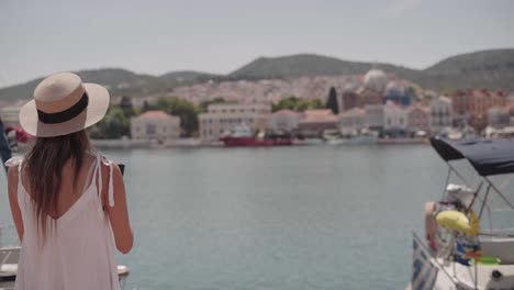 solo female traveler in white dress takes a picture of the coastal mitilini coastline on the island of lesvos, greece