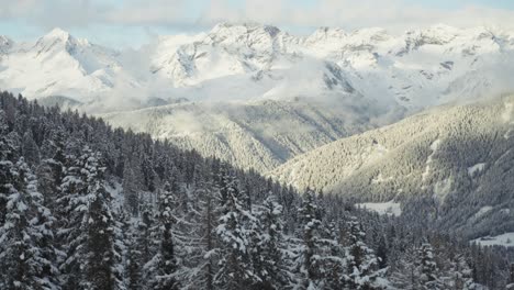 the italian alps shine under sunlight, with forested ridges and snowy meadows spread below. parallax video.