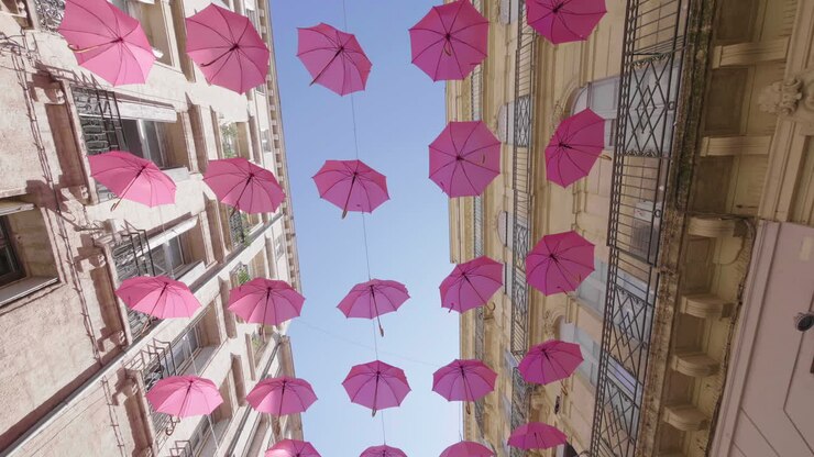 Ombrelli rosa sospesi tra due edifici a Montpellier. Ottobre Rosa