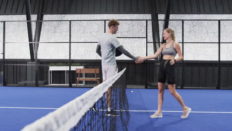 young man and woman discussing strategy on indoor padel tennis indoor court, holding rackets