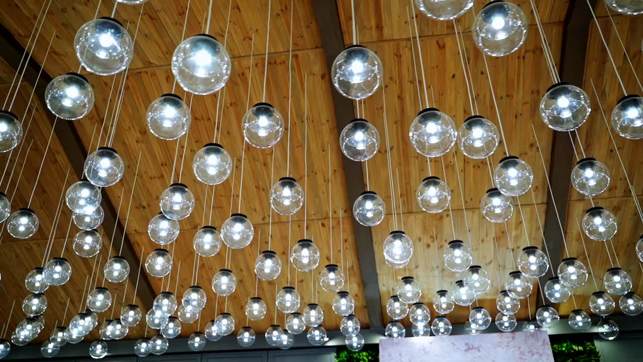 Creative interior of many lamps. Modern ceiling lighting of hanging light bulbs indoors.