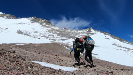 two climbers with heavy backpacks hiking towards camp cholera on the ascent to aconcagua