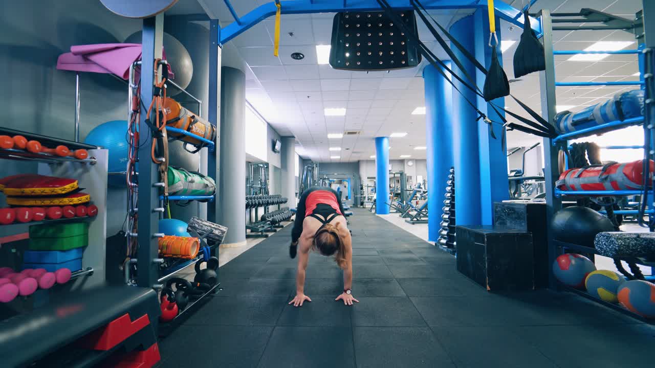 Front view of a muscular woman in the gym. Fitness girl training her body in the modern sports center. Daily workout. Healthy lifestyle.
