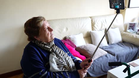 abuela elegante tomando selfies con su teléfono inteligente usando un palo de selfie