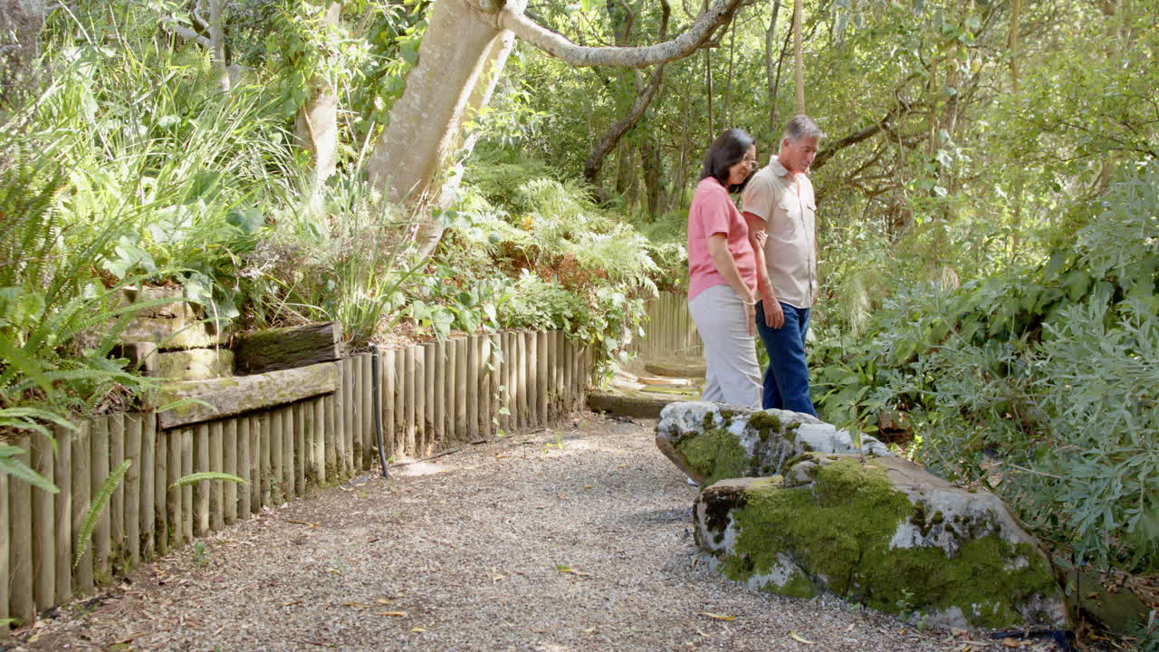 Senior diverse couple gardening together in lush backyard, enjoying nature and fresh air