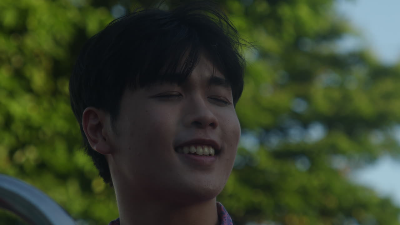 가까운 아시아 남성 은 빛 을 즐기고 도시 풍경 과 비누 거품 을 배경 으로 음악 을 들으면서 미소 짓고 있다