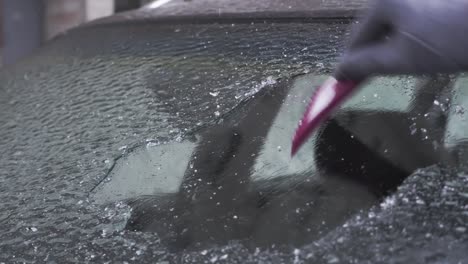 woman scrapes ice off the windshield of her car after a long parking lot.