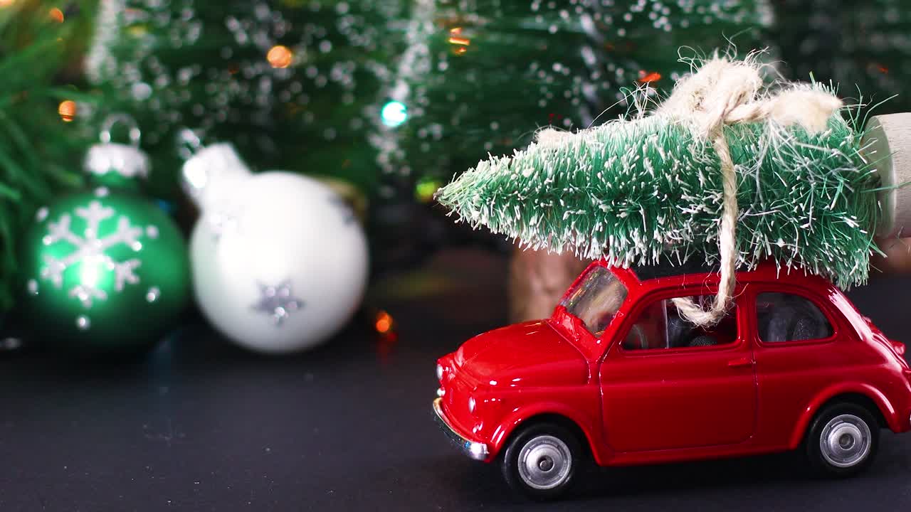 Blinking Christmas lights on winter decoration with ornaments and vintage red car with Christmas tree on roof