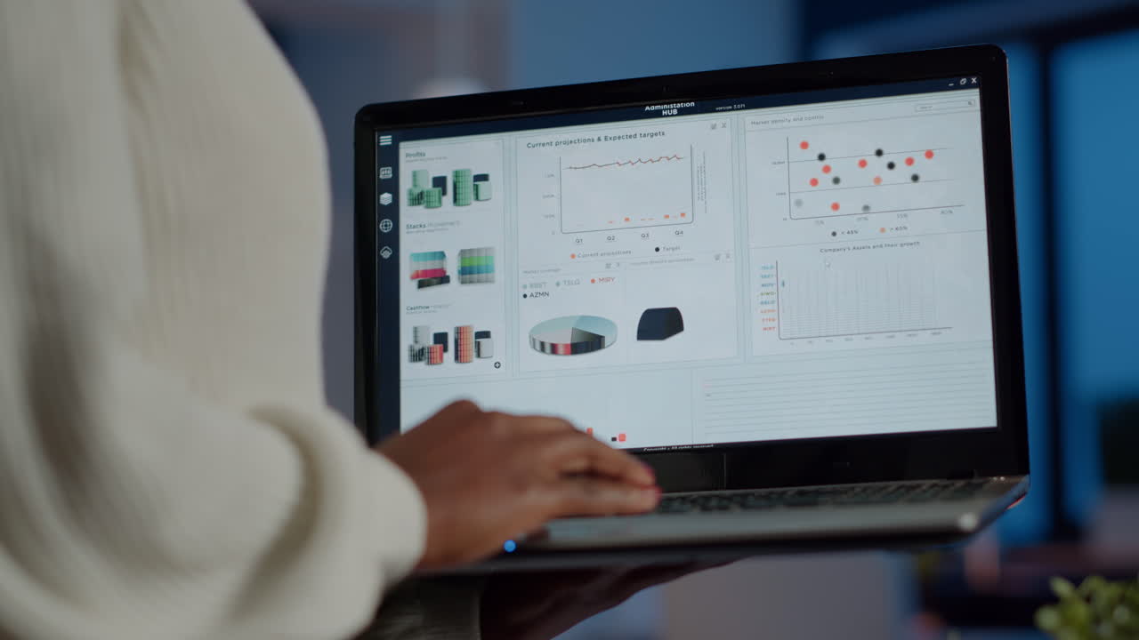 Back view of african business woman analysing financial statistics holding laptop