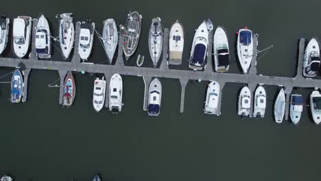 top down aerial drone view above luxury moored private marina sailing ships and yacht boats moving forwards