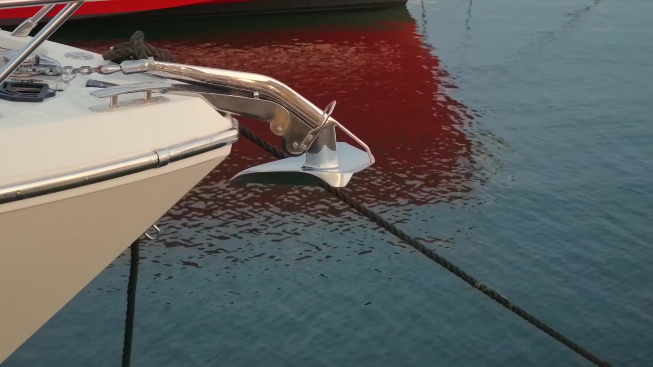 Primo piano di un'ancora di barca e degli accessori di prua con un'altra barca riflessa nell'acqua, Golfe-Juan, Francia