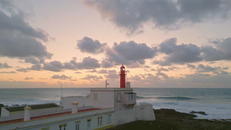 Lighthouse lit golden sundown drone view. Picturesque golden sunset over ocean