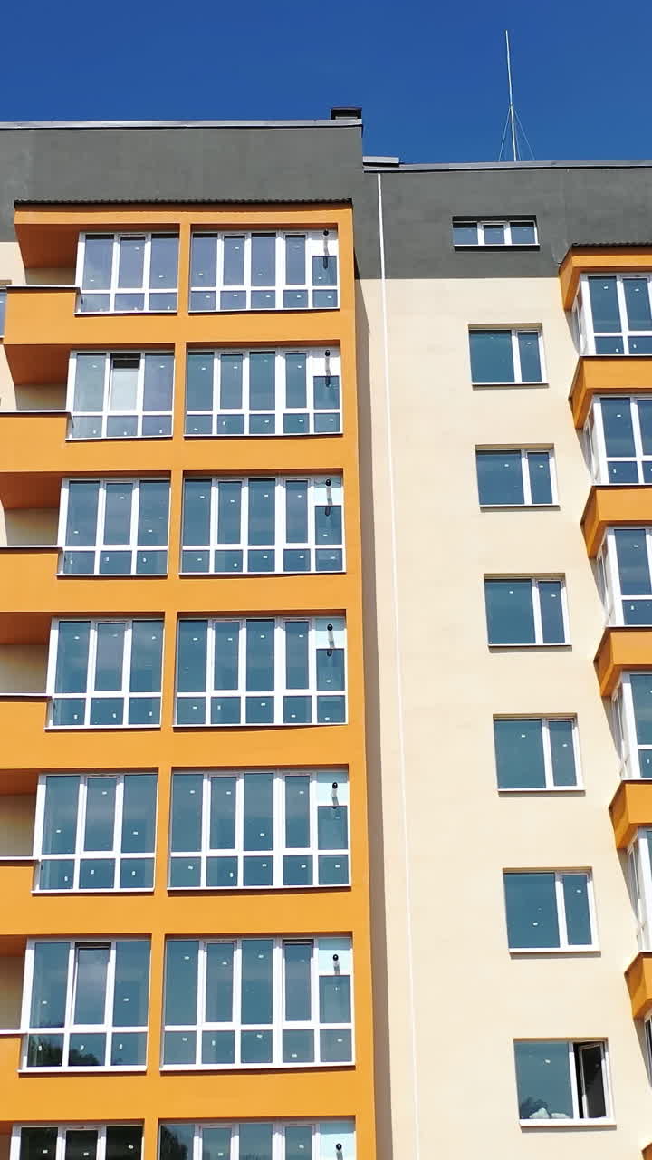 Facade of a new apartment building. Modern multi storey house with bright walls. Block of flats with large balconies. Front view. Vertical video
