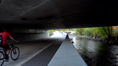 Biker-riding-on-bike-path-along-a-creek-in-slow-motion