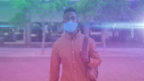 blue light spots against portrait of african american man wearing face mask standing on the street