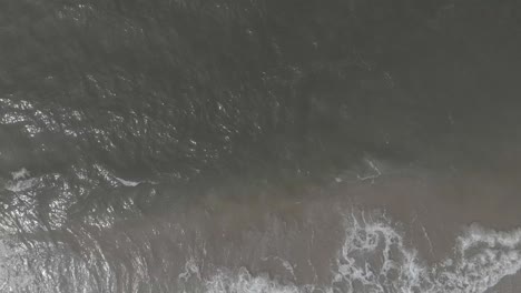 calm waves of baltic sea breaking on empty beach aerial view
