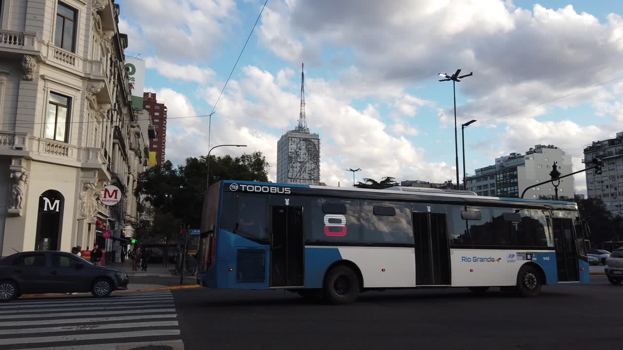 Traffic at Mayo Avenue Buenos Aires city with Eva Peron Evita building background, skyline with public buses cars and taxis driving through fast lane crossing 9 de Julio