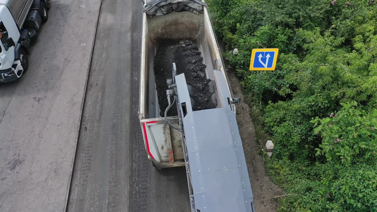 Heavy machinery at roadworks. Special machinery loading truck with asphalt on the road. Reconstruction on the highway. Aerial view.