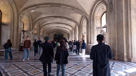 people walking through a grand museum corridor